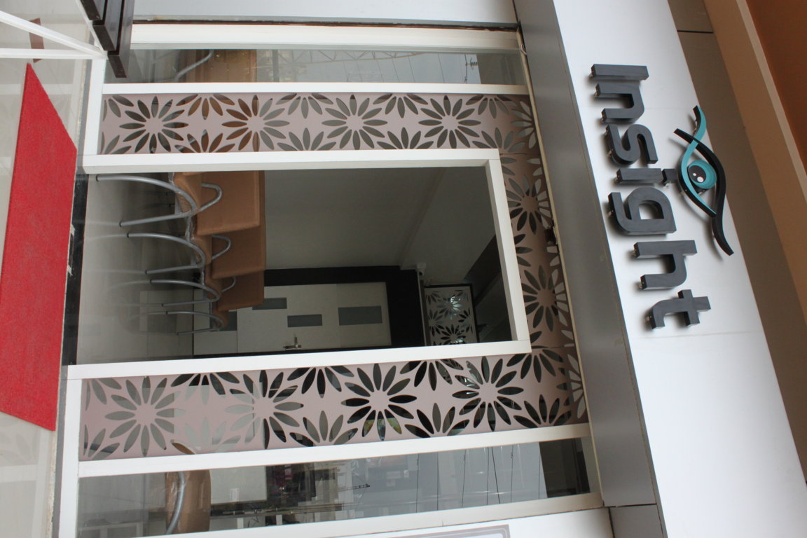 Insight Institute main entrance framed by tall laser-cut floral metalwork panels and full-height glazing reflecting the daylight